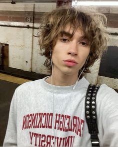 a young man with ear buds on his ears is standing in an empty room and looking at the camera