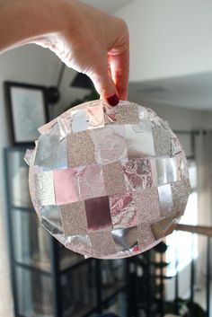 a person is holding up a glass ornament that has been cut into squares