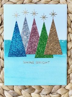 a card with three christmas trees on it and the words shine bright written in gold