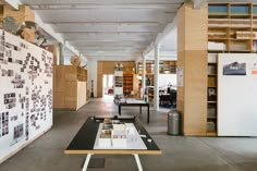 an open room with tables and pictures on the wall, in front of bookshelves