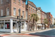 an empty street with several stores on the corner and palm trees in front of them