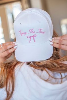 a woman wearing a white hat with pink lettering on it