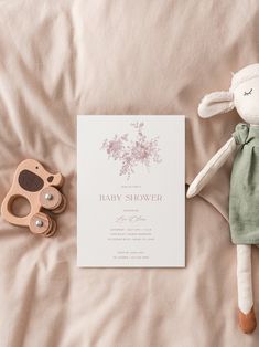 a baby shower is next to a wooden toy and card on a bed with pink sheets