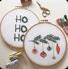 two embroidery hoops with christmas ornaments hanging from them and some thread spools