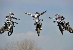 three motorcyclists are jumping in the air on their bikes and doing tricks