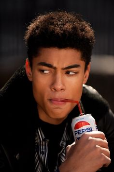 a close up of a person holding a can of pepsi with a straw in his mouth