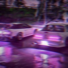 two cars parked next to each other in a parking lot with purple lights on them