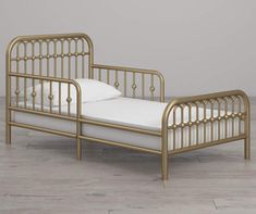 a gold metal bed frame with white sheets