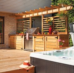 a hot tub sitting on top of a wooden deck next to a bbq grill