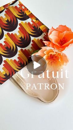 an orange flower sitting on top of a white table next to a bag with the words crutt patron