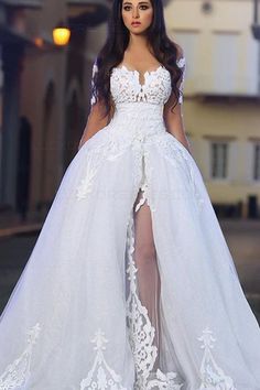 a woman in a white wedding dress standing on the street with her legs slited