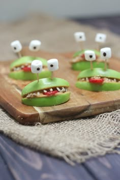 some food that is on top of a wooden board with marshmallows in the shape of eyes