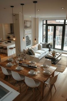 a living room filled with furniture and a wooden table in front of a large window