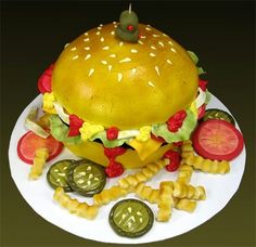 a cake made to look like a hamburger with fries and pickles on the side