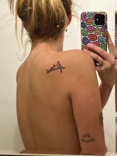 a woman taking a selfie in front of a mirror with her tattoo on her back