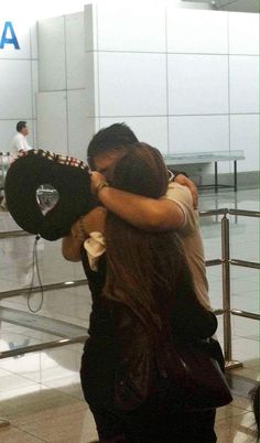 two people hugging each other in an airport