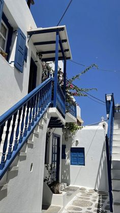 an alleyway with blue shutters and flowers on the balconies in mykonos, greece