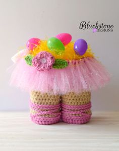 a crocheted basket with easter eggs and flowers on the top, sitting on a table