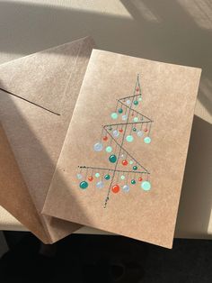 two christmas cards on top of each other next to a brown envelope with an ornament