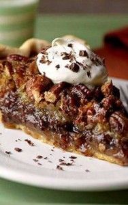 a slice of pecan pie with whipped cream on top sits on a white plate