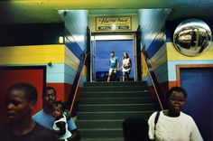 several people are standing on the stairs in front of a building with blue and yellow walls