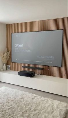 a flat screen tv mounted to the side of a wall in front of a white rug