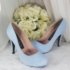 a pair of blue high heels sitting next to a bouquet of white roses