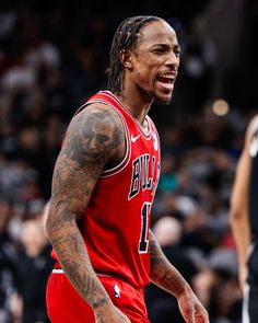 a man with dreadlocks and tattoos on his face is walking in front of an audience