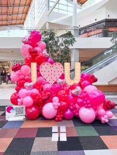 there is a large pile of balloons in the shape of a tree that says u