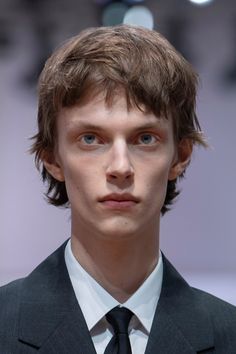 a young man in a suit and tie looking at the camera with serious expression on his face