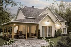 a small white house with a covered porch and patio area next to it is surrounded by greenery