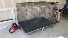 a man in grey shirt working on a metal cage with black flooring and walls