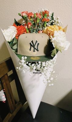 a baseball cap with flowers in it sitting on top of a white cone shaped vase