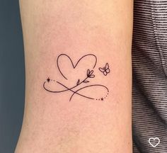 a small heart tattoo on the arm with butterflies flying around it and stars in the sky