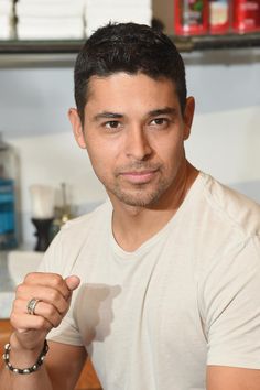 a man in a white t - shirt is posing for the camera with his finger up