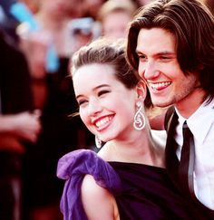 two people standing next to each other on a red carpet smiling at the camera,