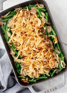 green beans, onions and mushrooms in a casserole dish on a marble surface