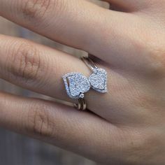 a woman's hand with two rings on it and an open heart shaped diamond ring