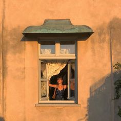 a woman is looking out the window with her arm in the air while standing outside