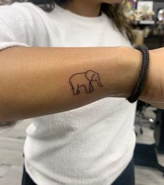 a woman with a small elephant tattoo on her left arm and the outline of an elephant