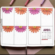 an open planner with pink and orange flowers on it, next to two pencils