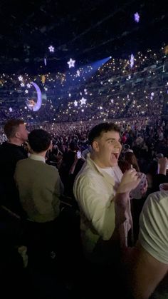 a group of people standing in front of a crowd at a music concert with confetti falling from the ceiling