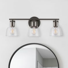 a bathroom vanity with three lights and a mirror on the wall next to it,