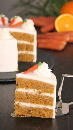 two slices of carrot cake with white frosting on a black plate and oranges in the background