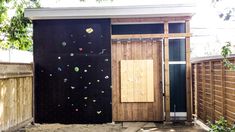 an outhouse with climbing wall and wooden door