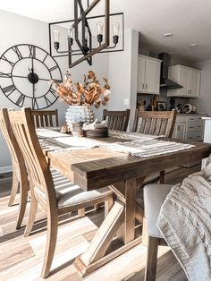 a dining room table and chairs with a clock in the background