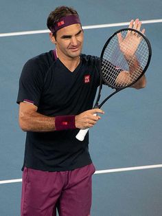 a man holding a tennis racquet on top of a tennis court with his hand in the air