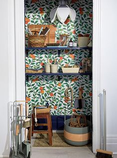 an open closet with wallpaper and baskets on the shelves in front of it's doors