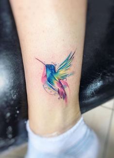 a colorful hummingbird tattoo on the ankle is shown in blue, pink and yellow