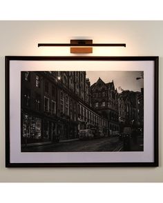 a black and white photo hanging on the wall next to a light that is above it